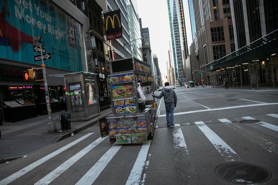 A food truck vendor pushes his cart down an empty street near Times Square in New York, on Sunday, March 15, 2020.