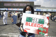 A woman hold a banner as she demonstrates on the street to protest against police brutality in Lagos, Nigeria, Sunday Oct. 18, 2020. Nigerian protests against police brutality continued Sunday for the eleventh day, with demonstrators fending off attacks from gangs suspected to be backed by the police, warnings from the Nigerian military, and a government order to stop because of COVID-19. (AP Photo/Sunday Alamba)