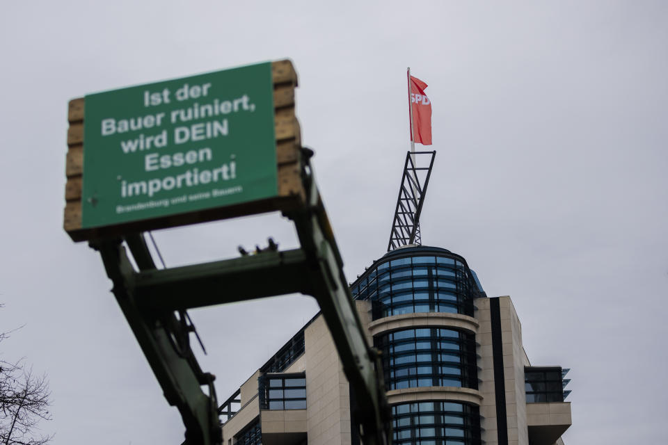 A tractor with a poster stands in front of the Willy Brandt House (SPD headquarters) during a protest with a tractor parade organized by the Brandenburg Farmers' Association against the increase in the tax on agricultural diesel, in Berlin, Germany, Friday Jan. 26, 2024. More than 300 farmers from the federal state of Brandenburg drove to Berlin from different directions on Friday morning. (Christoph Soeder/dpa via AP)