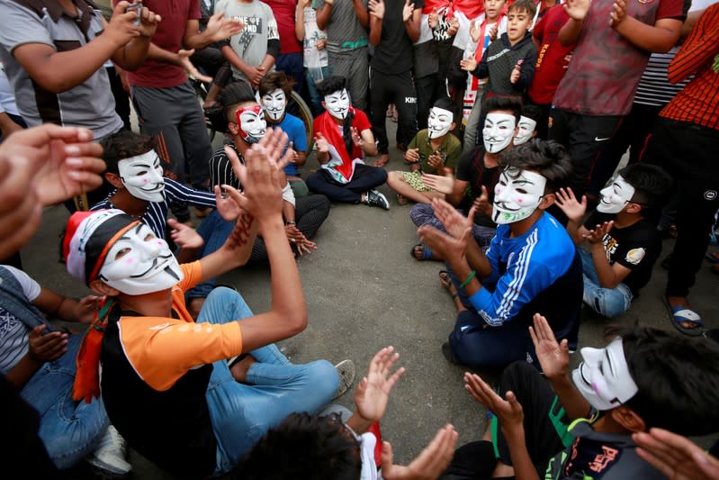 Demonstrators wear masks and shout slogans during ongoing anti-government protests in the holy city of Najaf