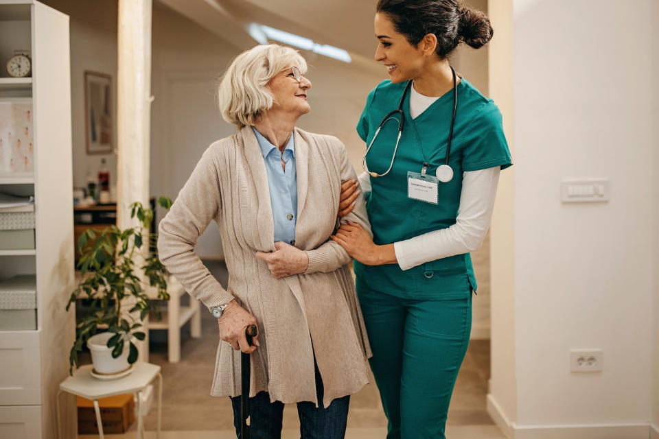 a nurse helping a lady with a cane