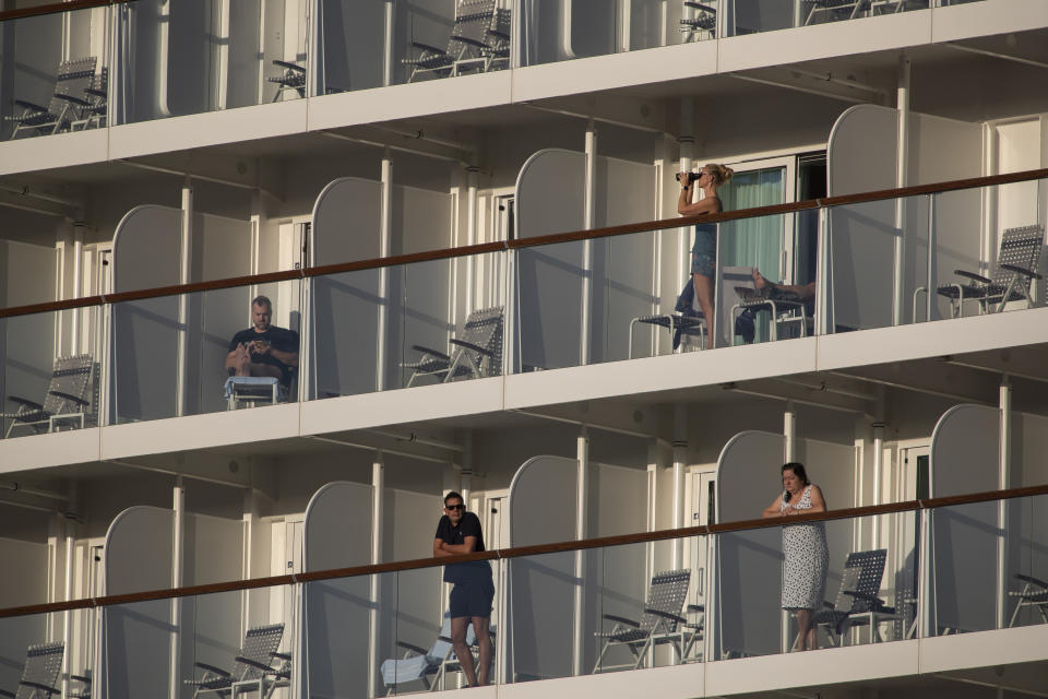 Passengers of the Mein Schiff 6 cruise ship stand outside their cabins as the ship is docked at Piraeus port, near Athens on Tuesday, Sept. 29, 2020. Greek authorities say 12 crew members on a Maltese-flagged cruise ship carrying more than 1,500 people on a Greek islands tour have tested positive for coronavirus and have been isolated on board. (AP Photo/Petros Giannakouris)