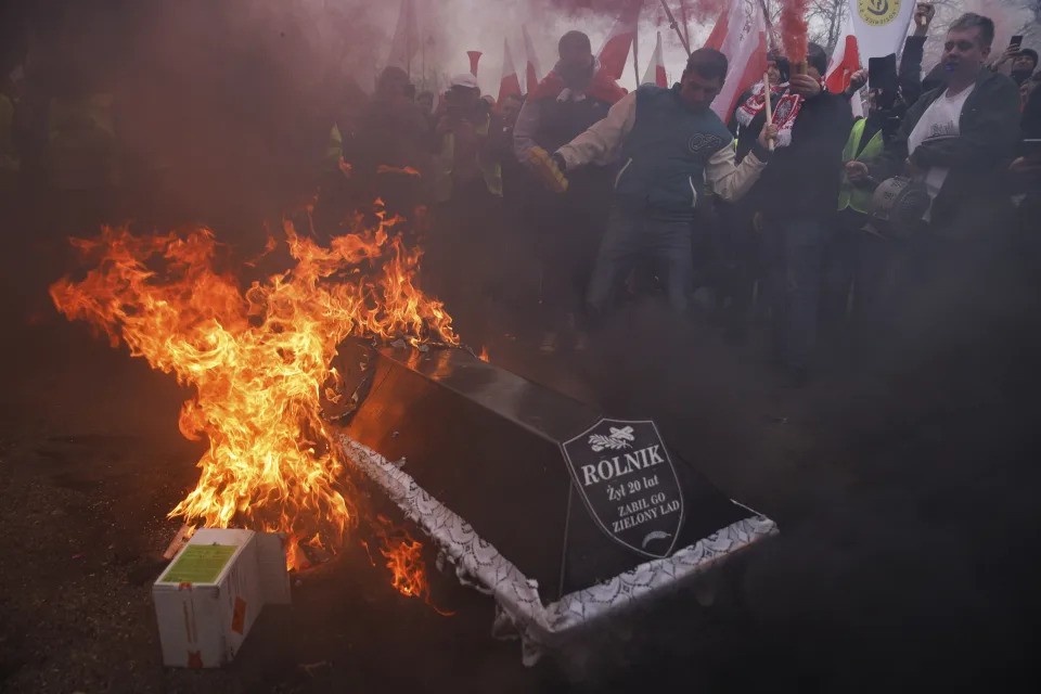 Demonstrators symbolically burn a coffin with the word "farmer" written on it during a protest in Warsaw, Poland, on Wednesday, March 6, 2024. The protest ratchets up pressure on the government as they demand the Poland-Ukraine border closed to food imports and demand changes to European Union climate and agricultural policies. (AP Photo/Michal Dyjuk)