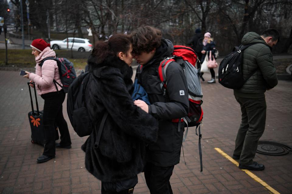 TOPSHOT - People hug as a woman with a suitcase passes by outside a metro station in Kyiv in the morning of February 24, 2022. - Russian President Vladimir Putin announced a military operation in Ukraine on Thursday with explosions heard soon after across the country and its foreign minister warning a 