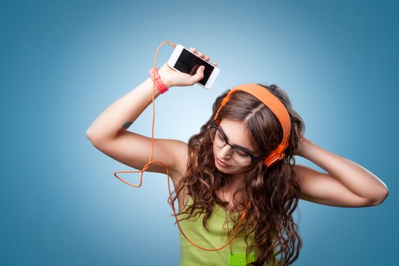 Girl listening to music on her smartphone with headphones and dancing