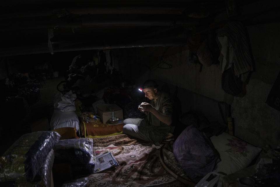 Un hombre ucraniano come en el interior de un sótano utilizado como refugio improvisado antibombas el viernes 13 de mayo de 2022, en Kutuzivka, en el este de Ucrania. (AP Foto/Bernat Armangue)