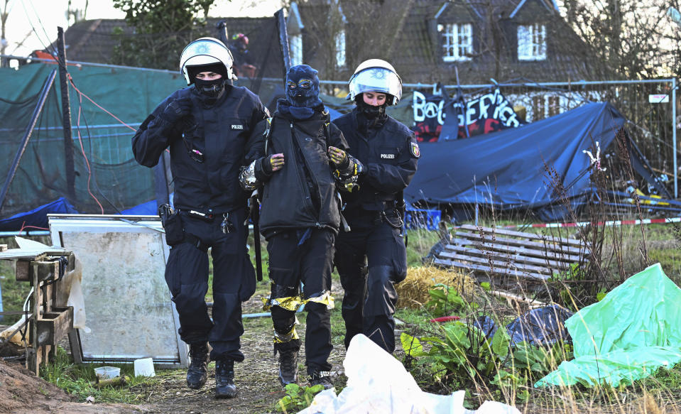 Police officers lead a climate activist off the site in the village Luetzerath in Erkelenz, Germany, Sunday, Jan. 15, 2023. The energy company RWE wants to excavate the coal lying under Luetzerath, for this purpose, the hamlet on the territory of the city of Erkelenz at the opencast lignite mine Garzweiler II is to be demolished. (Federico Gambarini/dpa via AP)