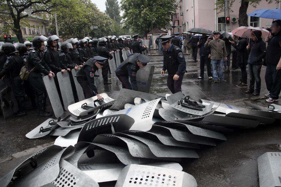 Ukrainian police officers remove shields which their comrades from another unit layed down earlier outside the police headquarter in Odessa, Ukraine, Sunday, May 4, 2014. Hundreds of pro-Russian demonstrators stormed police headquarters in Odessa on Sunday and won the release of 67 people detained after deadly clashes in the Ukrainian port city. More than 40 people died in the riots, which some from gunshot wounds, but most in a horrific fire that tore through a trade union building late Friday. (AP Photo/Sergei Poliakov)