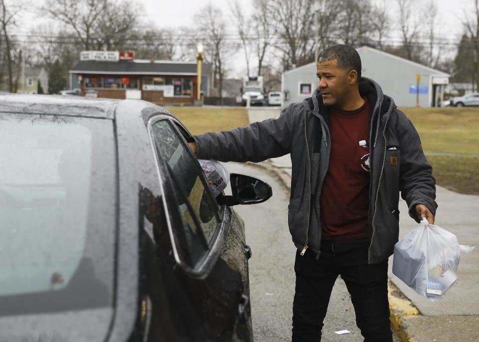 Joao Andrade, of Brockton, hands out grab-and-go meals to families at the East Middle School on Tuesday, March 17, 2020. The food services staff handed out meals every day for Brockton Public School students amid COVID-19 and remote learning.