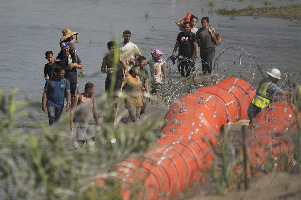 Migrants trying to enter the U.S. from Mexico approach the site where workers are assembling large buoys to be used as a border barrier along the banks of the Rio Grande in Eagle Pass, Texas, Tuesday, July 11, 2023. (AP Photo/Eric Gay)