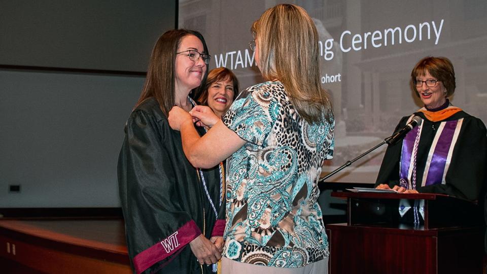 Jamie Crandall, a May graduate in nursing from Earth, is pinned by her sister, Heather Sauer, a registered nurse, during the annual pinning ceremony for West Texas A&M University's Laura and Joe Street School of Nursing. Also pictured are Katie Spear, second from left, instructor of nursing, and Laura Reyher, Baptist Community Services Professor of Rural Health.