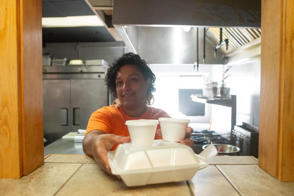 Chef Ambrosia Watson hands off a customer's order of ribs with sides through the kitchen window of Soul Fire Food Co. on Friday.