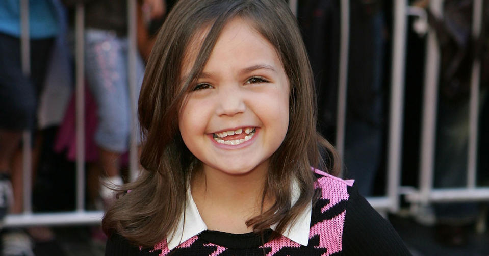 Bailee Madison smiling at the camera as a young child. She has one missing tooth.