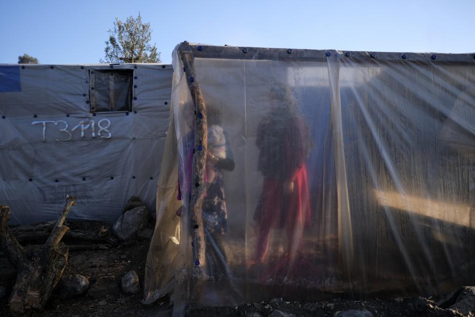 Migrants stand next to tents outside the Moria refugee camp on the northeastern Aegean island of Lesbos, Greece, on Wednesday, Jan. 22, 2020. Some businesses and public services on the eastern Aegean island are holding a 24-hour strike on Wednesday to protest the migration situation, with thousands of migrants and refugees are stranded in overcrowded camps in increasingly precarious conditions. (AP Photo/Aggelos Barai)