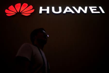 FILE PHOTO: A man walks past a sign board of Huawei at CES (Consumer Electronics Show) Asia 2018 in Shanghai, China June 14, 2018. REUTERS/Aly Song/File Photo