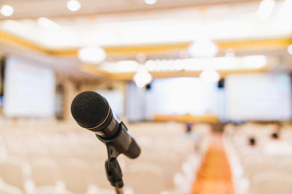 A microphone on a stand in front of an empty auditorium.