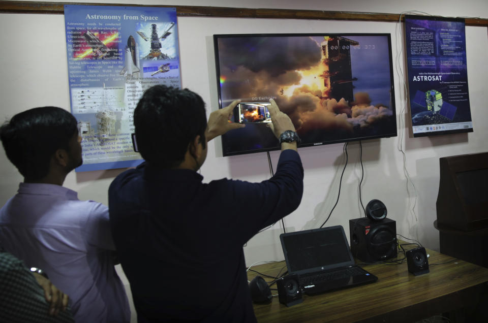 Indians at New Delhi's Nehru Planetarium, watch a web cast of the lift off of Indian Space Research Organization (ISRO)'s Geosynchronous Satellite launch Vehicle (GSLV) MkIII carrying Chandrayaan-2 from Satish Dhawan Space center in Sriharikota, India, Monday, July 22, 2019. India's space agency says it has launched an unmanned spacecraft to the far side of the moon a week after aborting the mission due to a technical problem. (AP Photo/Manish Swarup)