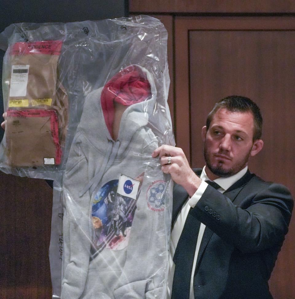City of Waukesha Police Department Warrant Specialist Kyle Becker holds up evidence exhibits during the trial of Darrell Brooks Wednesday at the Waukesha County Courthouse. Brooks is charged with driving into the Waukesha Christmas Parade last year, killing six people and injuring dozens more.