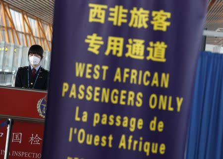 A quarantine official stands behind a banner notifying to incoming passengers from West Africa's Ebola haemorrhagic fever outbreak countries to use a specific lane for quarantine check at an arrival terminal of the Beijing Capital International Airport October 30, 2014. REUTERS/Kim Kyung-Hoon