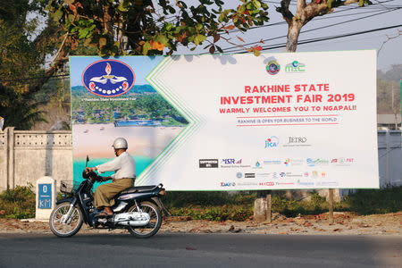 A rider passes by the Rakhine State Investment Fair 2019 bulletin board in Ngapali beach in Thandwe, Rakhine State, Myanmar February 19, 2019. REUTERS/Ann Wang