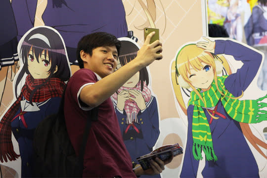 A fan posing with the cardboard of an anime. (Photo: Sharlene Sankaran/Yahoo Singapore)