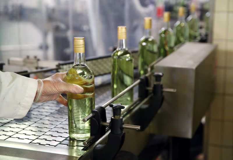 Staff lines a bottle into a labeller at Swiss distiller Morand in Martigny