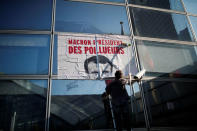 A poster which reads "Macron, President of polluters" is seen as environmental activists block the entrance of the Ministry of Ecology, Energy and Sustainable Development during a "civil disobedience action" to urge world leaders to act against climate change, in La Defense near Paris, France, April 19, 2019. REUTERS/Benoit Tessier