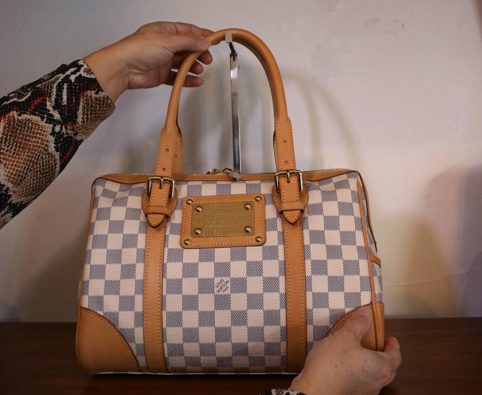 Owner Krista Hanny puts a Louis Vuitton Berkeley Handbag on display inside her new store FOMO on South Avenue in Rochester Tuesday, Dec. 14, 2021.  