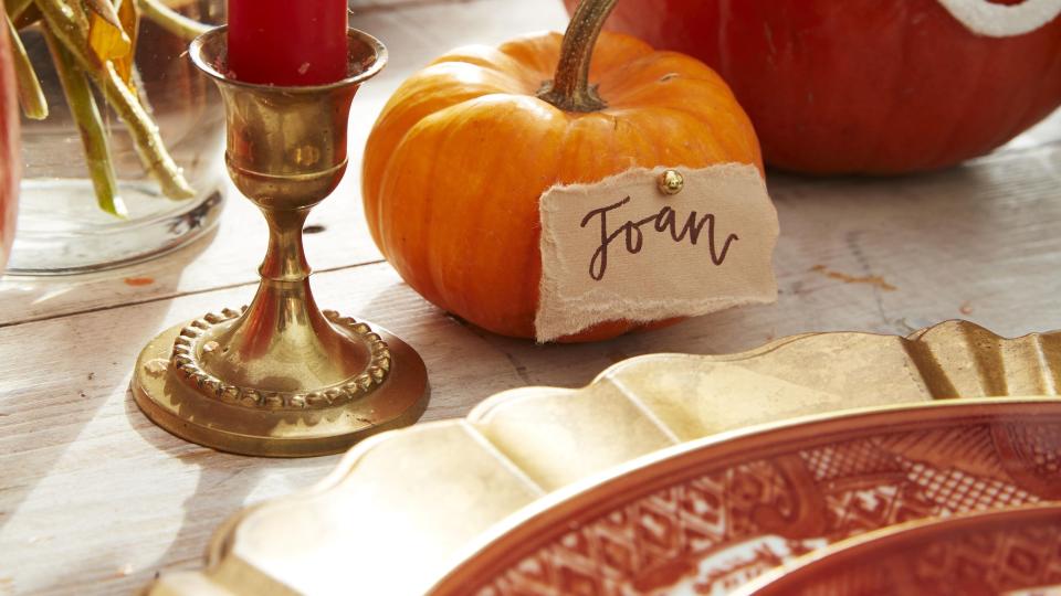 mini orange pumpkin turned into a place card on a thanksgiving table