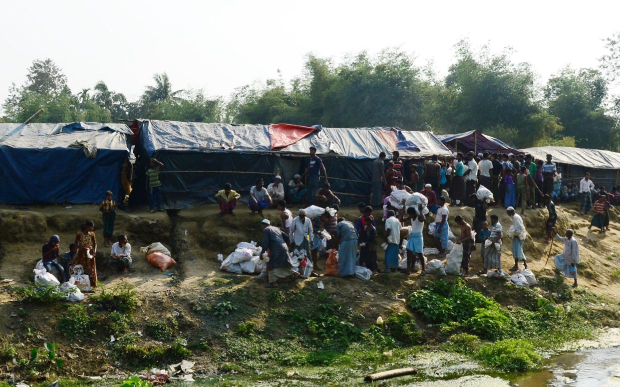 Rohingya refugees collect relief material next to a settlement near the 'no man's land' area between Myanmar and Bangladesh - AFP