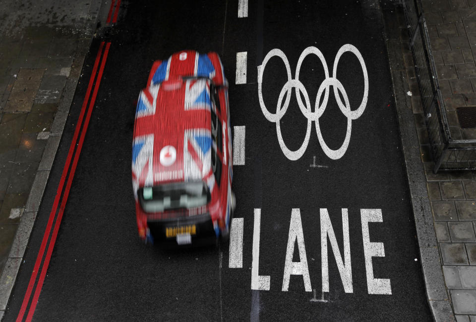 A taxi cab drives past an Olympic lane on a street as the city prepares for the 2012 Summer Olympics, central London, Monday, July 16, 2012. (AP Photo/Charlie Riedel)