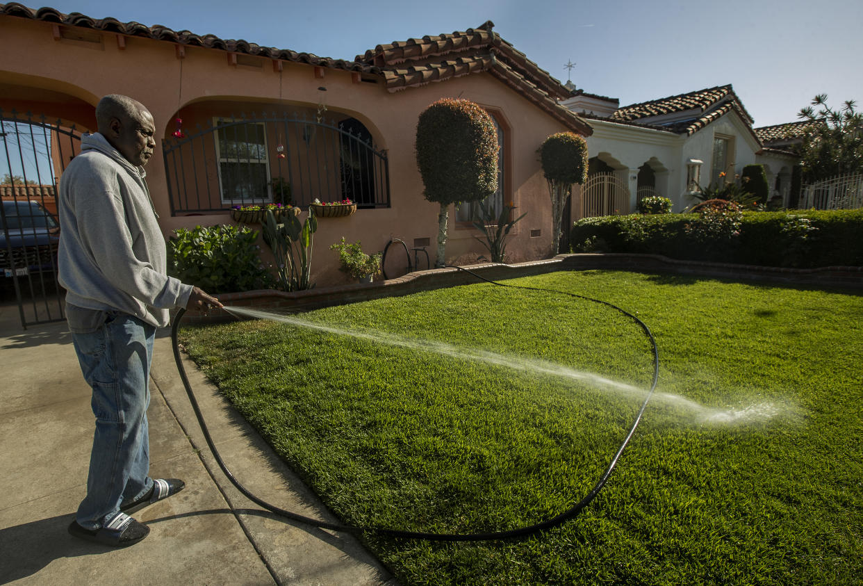 Keith Lewis waters his lawn in front of his home on 81st Place in Los Angeles.