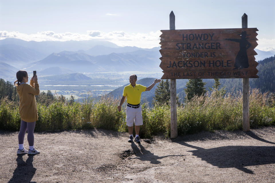 Kao Vang, of Detroit, Mich., photographs her husband Jeffery at the top of Teton Pass in Wilson, WY. on Aug. 23, 2023. After two years of a red-hot post-pandemic recovery nearby Jackson, WY., is returning to something like normal, with sustainable spending and less inflationary conditions the Federal Reserve would like to see nationwide. (AP Photo/Amber Baesler)