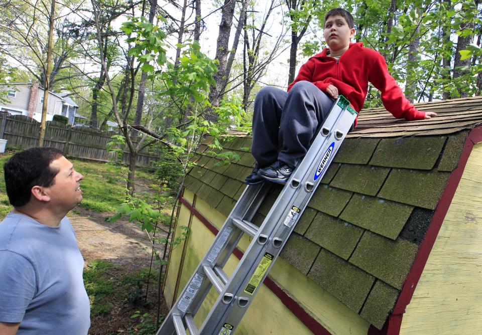 Stuart Chaifetz looks at his son Akian Chaifetz, 10, as he sits on top of a ladder at their home in Cherry Hill, N.J., Wednesday, April 25, 2012. Chaifetz was told that his son Akian was acting violently at his New Jersey school -- including physical assaults against his teacher and teacher's aide -- so he decided to investigate. Akian has autism, as do the rest of the students in the class. This prevented him from being able to explain to his father if anything had been happening to him at school. Chaifetz decided the only way to find out what was behind the outbursts was to send his boy to school wearing a hidden audio recorder. (AP Photo/Mel Evans)