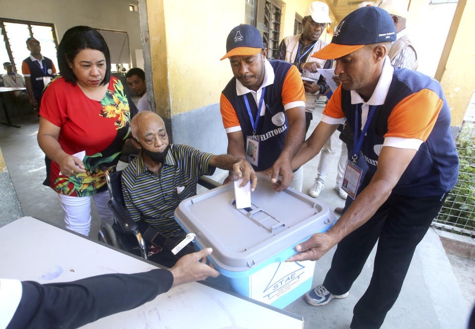 Electoral workers assist a man in a wheelchair to cast his ballot at a polling station during the parliamentary election in Dili, East Timor, Sunday, May 21, 2023. East Timor on Sunday held its fifth parliamentary election since gaining its independence in 2002. (AP Photo/Lorenio L.Pereira)