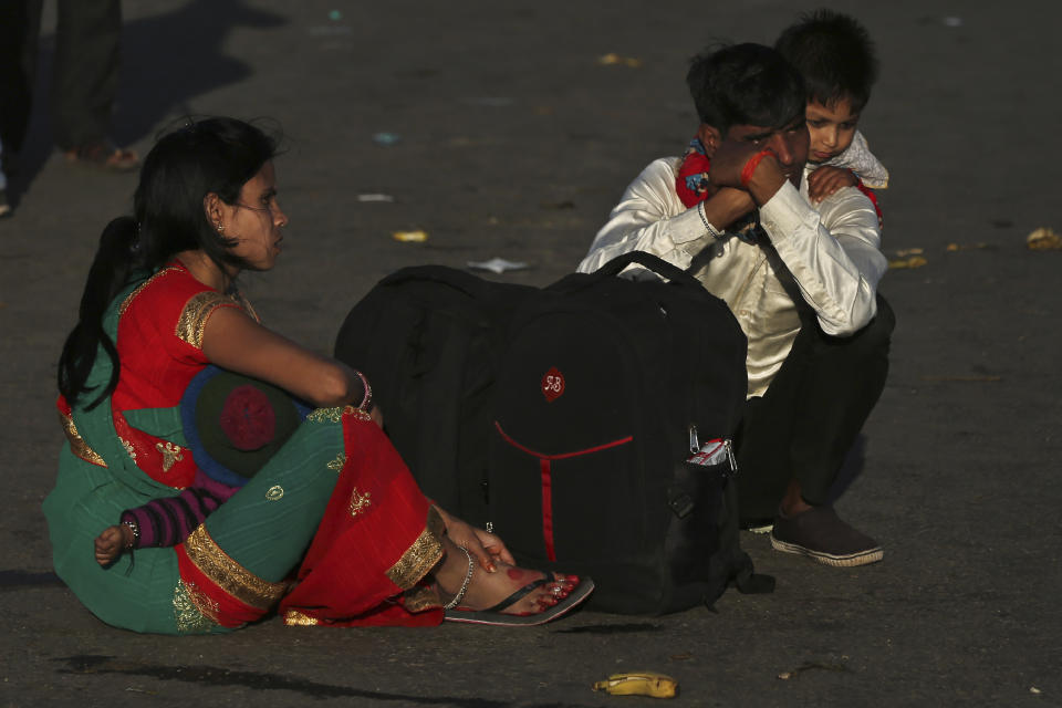 An Indian migrant worker carries a child on his shoulders as they wait for transportation to their village following a lockdown amid concern over spread of coronavirus in New Delhi, India, Saturday, March 28, 2020. Authorities sent a fleet of buses to the outskirts of India's capital on Saturday to meet an exodus of migrant workers desperately trying to reach their home villages during the world's largest coronavirus lockdown. Thousands of people, mostly young male day laborers but also families, fled their New Delhi homes after Prime Minister Narendra Modi announced a 21-day lockdown that began on Wednesday and effectively put millions of Indians who live off daily earnings out of work. (AP Photo/Altaf Qadri)