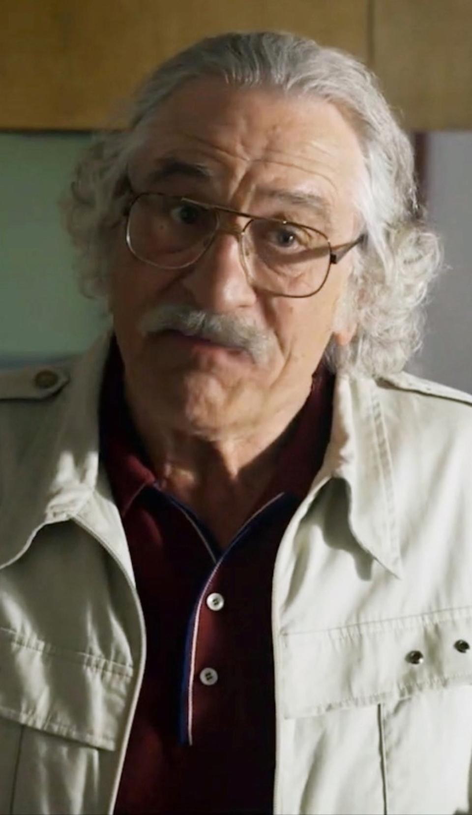 Robert De Niro with long grey hair, a grey beard, and over-sized glasses