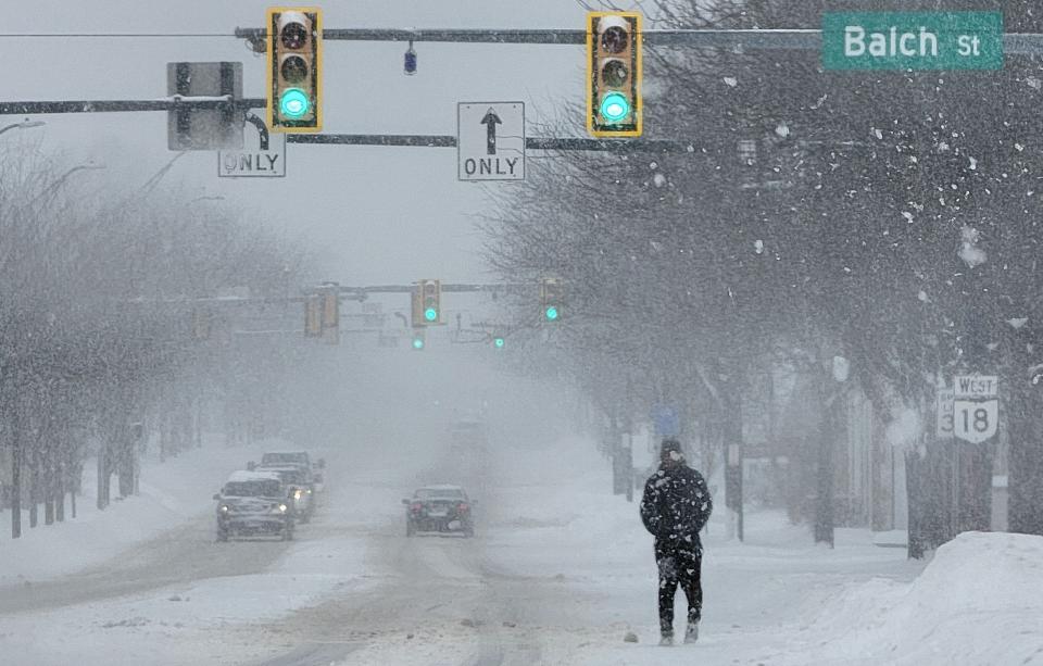 A man walks down West Market Street during a snowstorm Monday, Jan. 17, 2022 in Akron.