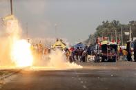 Flames emerge from tear gas released by the police to stop farmers opposing the newly passed farm bills from entering the national capital Delhi, at Singhu border, India