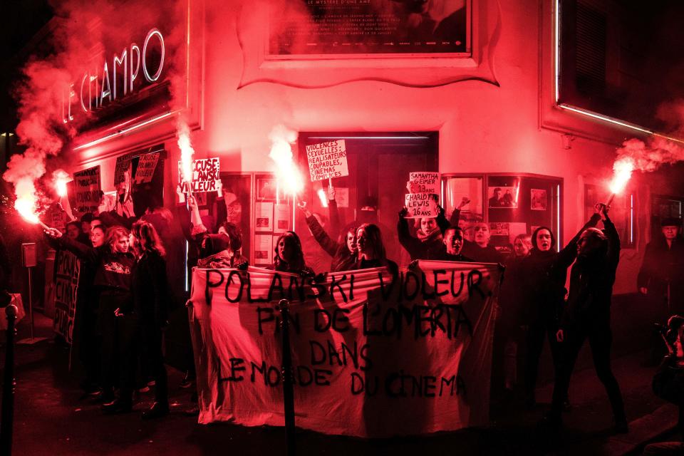 Demonstrators hold banners reading "Polanski rapist" as they hold flares during a protest against French-Polish film director Roman Polanski outside the "Champo" cinema hall in Paris on November 12, 2019. - Interviews to promote Polanski's new film "An Officer and a Spy" have been either cancelled or pulled after a new rape allegation against the controversial director on November 8. (Photo by Christophe ARCHAMBAULT / AFP) (Photo by CHRISTOPHE ARCHAMBAULT/AFP via Getty Images)