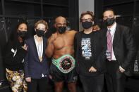 In a photo provided by Triller, Kiki Tyson, Sophie Watts, Mike Tyson, John Ryan and Azheem Spicer, from left, pose in the locker room after Tyson's exhibition boxing bout against Roy Jones Jr. on Saturday, Nov. 28, 2020, in Los Angeles. The bout was unofficially ruled a draw by the WBC judges at ringside. Tyson and Jones fought eight two-minute rounds, and both emerged smiling and apparently healthy from a highly unusual event. (Joe Scarnici/Triller via AP)