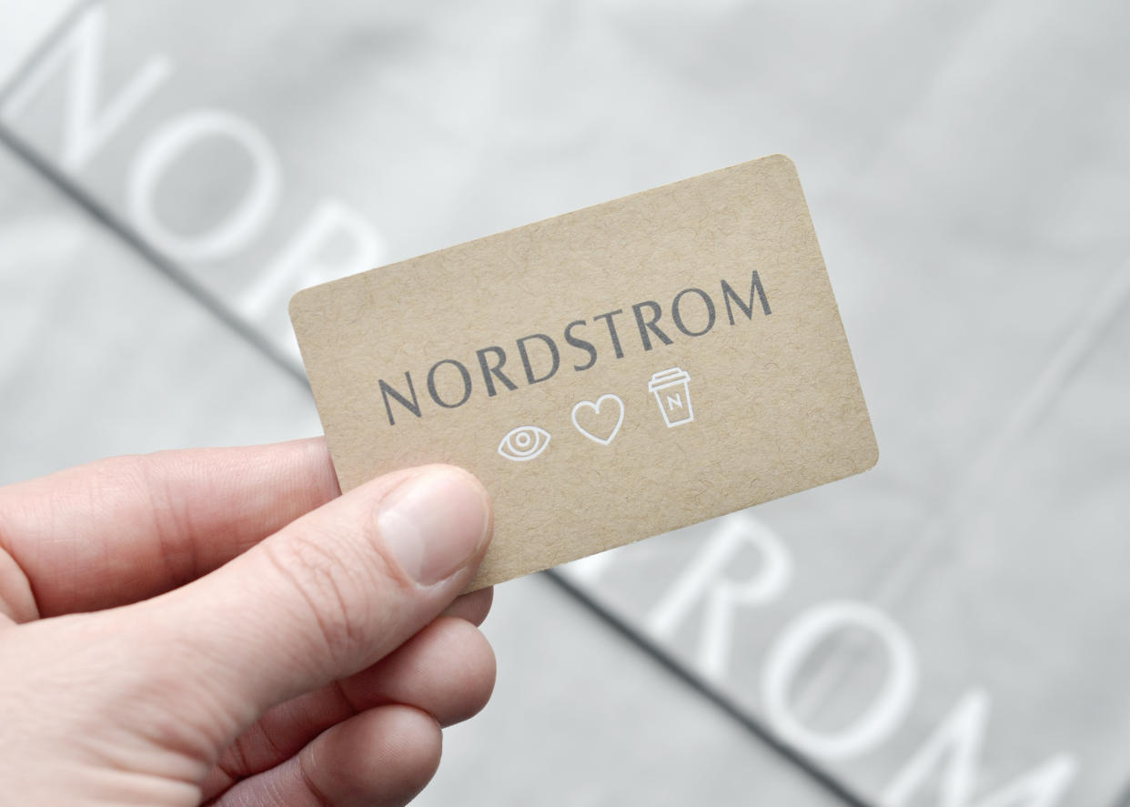 Vancouver, B.C., Canada -- February 4, 2015:Closeup of a man's hand holding a Nordstrom Gift Card above Nordstrom shopping bags.  Nordstrom is the largest upscale fashion retailer in the United States. 