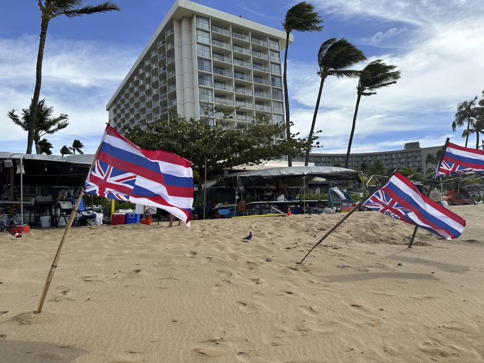 Upside down Hawaiian flags, a sign of distress, blow in the wind at a protest in front of resort hotels on Kaanapali Beach in Lahaina, Hawaii on Wednesday, Nov.14, 2023. A group of Lahaina wildfire survivors is vowing to camp on a popular resort beach until the mayor uses his emergency powers to shut down unpermitted vacation rentals and make the properties available for residents in desperate need of housing. (AP Photo/Audrey McAvoy)