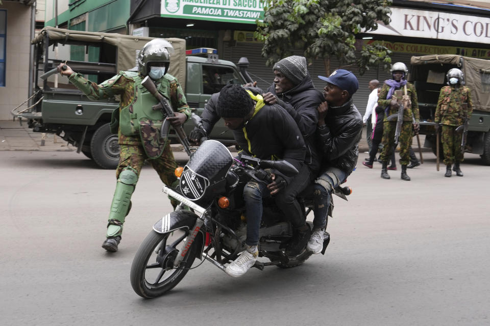 Kenya anti riot police beat people on a motorcycle in Nairobi, Kenya Thursday, June 27, 2024. Thousands of protesters stormed and burned a section of Kenya's parliament Tuesday to protest tax proposals. Police responded with gunfire and several protesters were killed. (AP Photo/Brian Inganga)