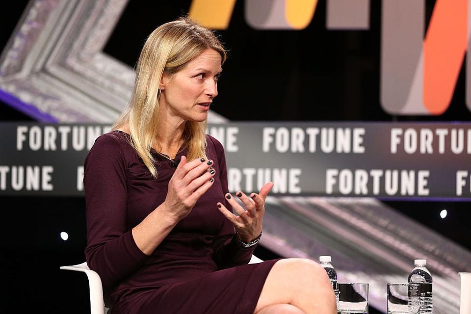 Katie Stanton sitting down and speaking, with her hands in front of her chest.