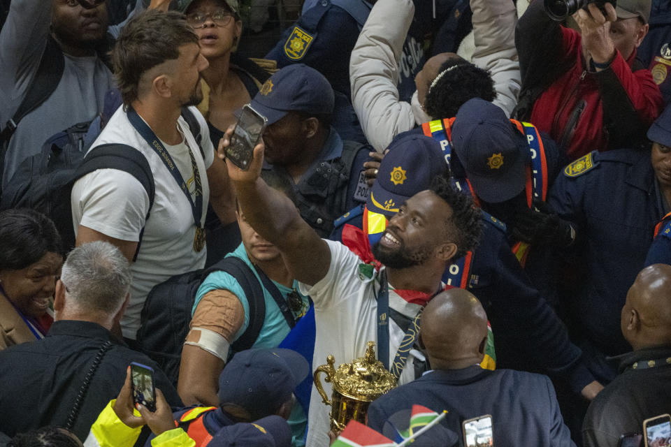 South Africa' Springbok captain Siya Kolisi takes a photo as he holds the Webb Ellis cup after arriving with other players at O.R Tambo's international airport in Johannesburg, South Africa, Tuesday Oct. 31, 2023, following the Rugby World Cup. (AP Photo/Jerome Delay)