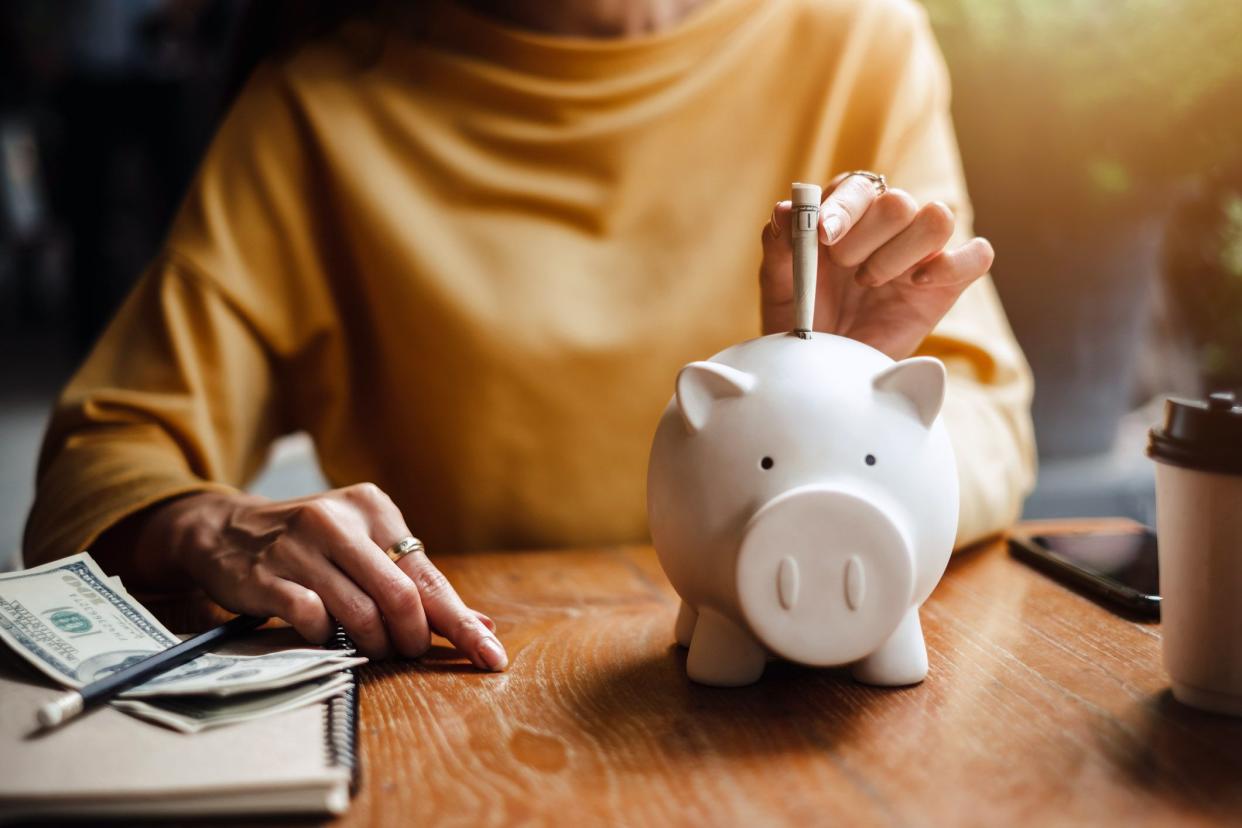 senior woman putting money in piggy bank