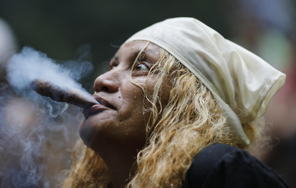 In this photo taken Oct. 12, 2019, a spiritual healer known as a "madrina" starts a ritual on Sorte Mountain where followers of indigenous goddess Maria Lionza gather annually in Venezuela's Yaracuy state. While her followers gather on the mountain for weeks at this time of the year, Oct. 12 marks the biggest gathering, coinciding with Indigenous People's Day, known in Latin America as "Dia de la Raza." (AP Photo/Ariana Cubillos)