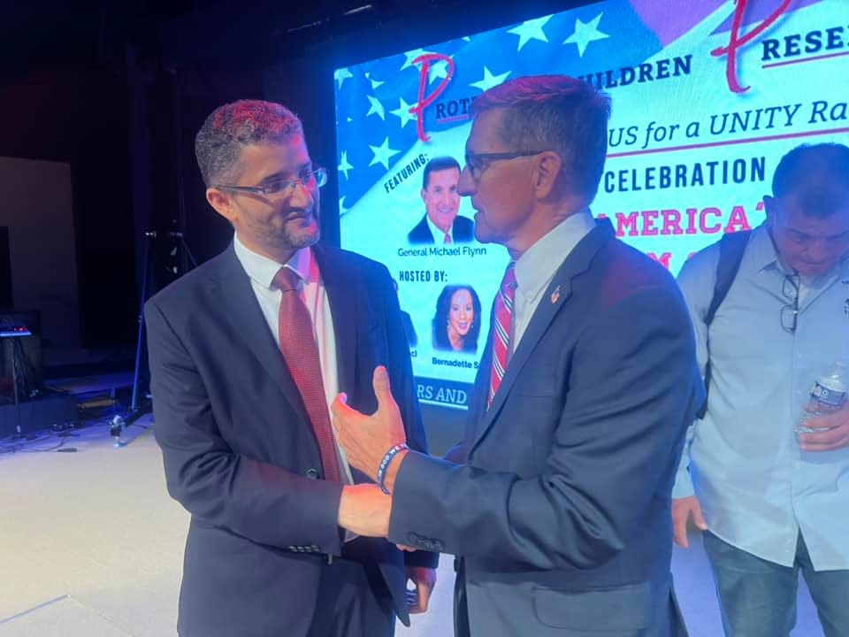 Hamtramck Mayor Amer Ghalib (left) speaks with Michael Flynn, former U.S. national security advisor under former President Donald Trump and retired three-star Army lieutenant general, on August 4, 2023, at Grace  Christian Church in Sterling Heights for an event, 'A Celebration of America's Freedom and Future.' A banner read "Protect Our Children" and "Preserve our Future." Part of Flynn's talk was criticized by some Jewish groups.