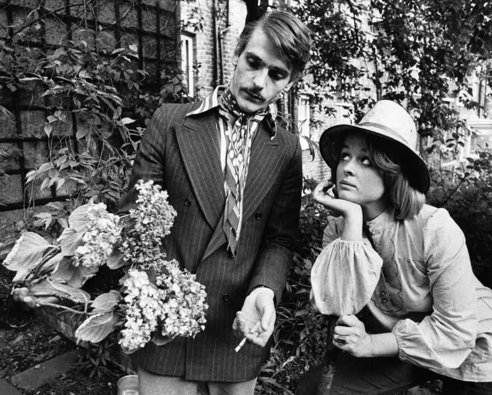 <p>English actor Jeremy Irons inspects a bouquet of hydrangeas from the garden at his Hampstead home in 1974 with his then-girlfriend, Sinead Cusack. </p>